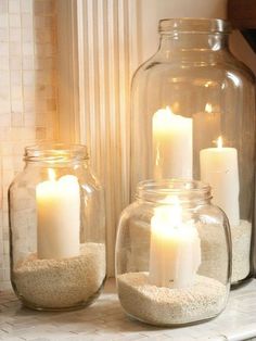 candles are lit in glass jars with sand inside