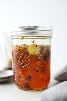 a glass jar filled with food sitting on top of a white table next to a spoon