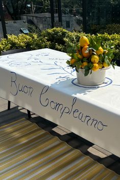 a white table topped with a vase filled with oranges