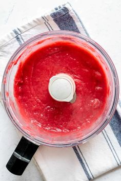 a food processor filled with red liquid on top of a towel