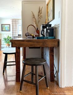 a wooden table sitting in the middle of a living room next to two stools