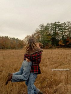 two people are hugging in the middle of a field