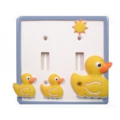 three yellow rubber ducks sitting in front of a white light switch plate with sun on it