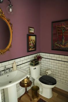 a bathroom with a toilet, sink and pictures on the wall above it's mirror