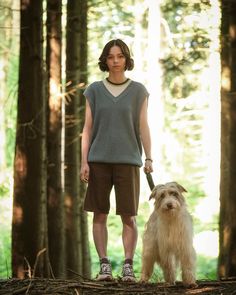 a person standing in the woods with a dog