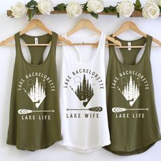 two tank tops hanging on a rack with flowers in the background and white roses behind them