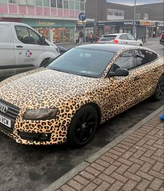 a leopard print car is parked on the side of the road in front of other cars