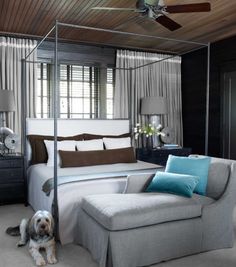 a bedroom with a canopy bed and a dog sitting on the floor next to it