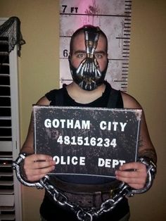 a man wearing a batman mask and holding a sign that says gotham city police dept