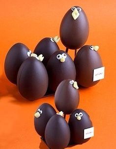 chocolate eggs with googly eyes are arranged on an orange surface