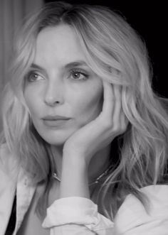 a black and white photo of a woman with her hand on her chin looking at the camera