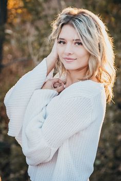 a woman in a white sweater posing for a photo with her hands on her hips