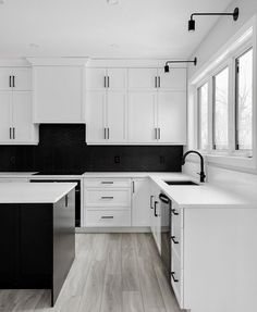 a kitchen with white cabinets and black backsplashes on the walls, along with an island countertop