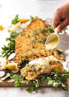 someone pouring dressing onto a chicken breast on a cutting board