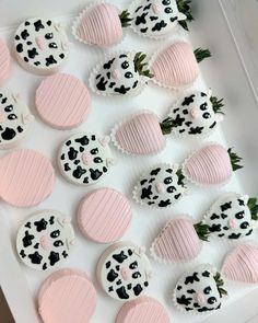 decorated cookies in pink and black on a white tray with strawberries next to them