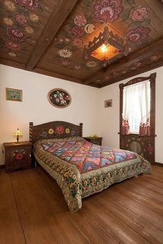 a bed sitting in a bedroom next to a window on top of a hard wood floor