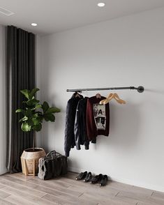 an open closet with clothes and shoes hanging on the rack, next to a potted plant