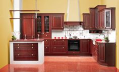 a kitchen with red tile flooring and wooden cabinets in the center, along with white counter tops