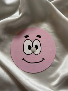 a close up of a pink object on a white cloth with a smiley face painted on it