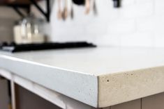 a counter top in a kitchen with utensils hanging on the wall behind it