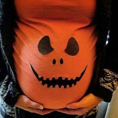 a pregnant woman wearing a pumpkin costume with her belly painted like a jack - o'- lantern