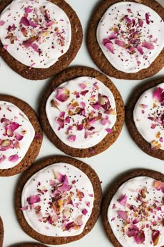 six cookies with white frosting and rose petals on them are arranged in a circle