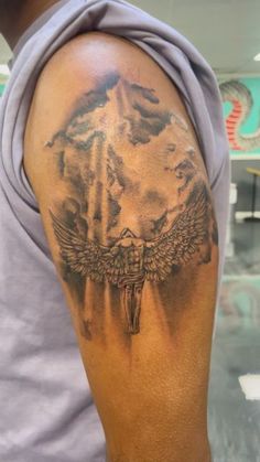 a man with a cross and wings tattoo on his arm