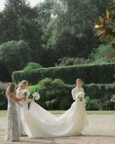 three women in dresses are standing near each other and one is holding a flower bouquet