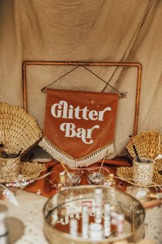 a table topped with baskets and plates covered in cloth next to a sign that says glitter bar