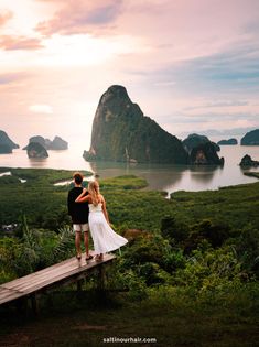 a man and woman standing on top of a wooden bench