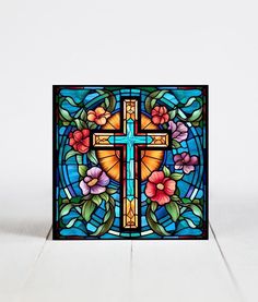 a stained glass window with flowers and a cross on it's side, against a white background