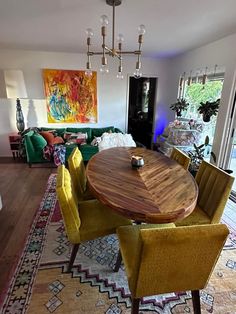 a dining room table with yellow chairs and a rug on the floor in front of it