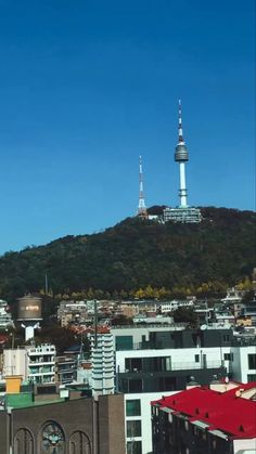 the city is surrounded by tall buildings and hills in the distance, with a clock tower on top