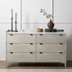 a white dresser with two vases and candles on top