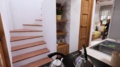 there is a sink and some tea kettles on the counter in this small kitchen