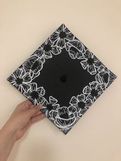 a hand holding a black and white graduation cap