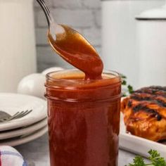 a spoon full of bbq sauce sitting on top of a table