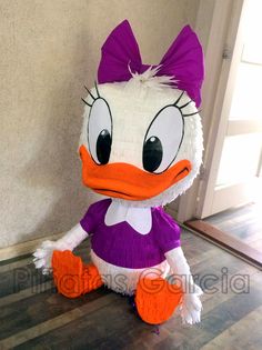 a large stuffed duck sitting on top of a hard wood floor next to a door