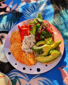 a white plate topped with vegetables and crackers on top of a blue table cloth