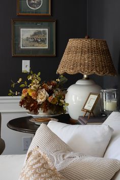 a white lamp sitting on top of a table next to a vase filled with flowers