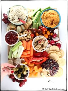 a platter filled with assorted fruits and veggies next to dips