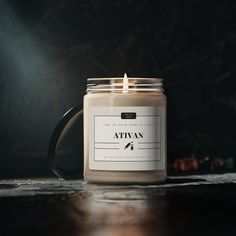 a lit candle sitting on top of a table next to a black mug with the words attivn written on it