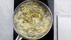 a pot filled with food sitting on top of a stove next to a white plate