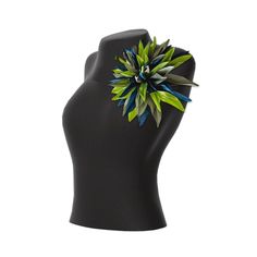 a black mannequin head with a green and blue flower on it's side