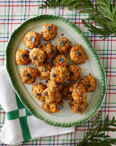 a white plate topped with cookies on top of a green and white table cloth next to evergreen branches