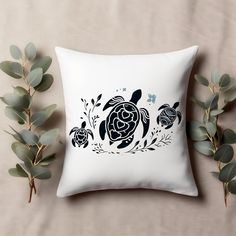 a pillow with an image of two sea turtles on it next to some green leaves