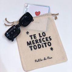 a pair of black sunglasses sitting on top of a white bag next to a card