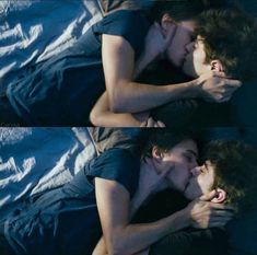 two people laying on top of each other with their faces close to one another and kissing