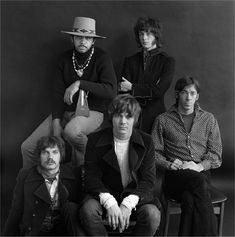 the rolling stones pose for a portrait in front of a black background, wearing hats and sweaters