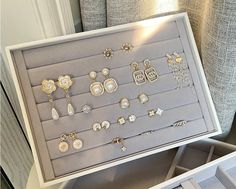 a display case with various pairs of earrings in it's tray on top of a table